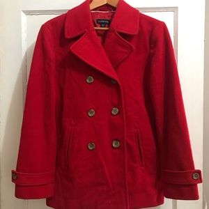 Classic red pea coat is double-breasted w/ button at collar. Slanted pockets.